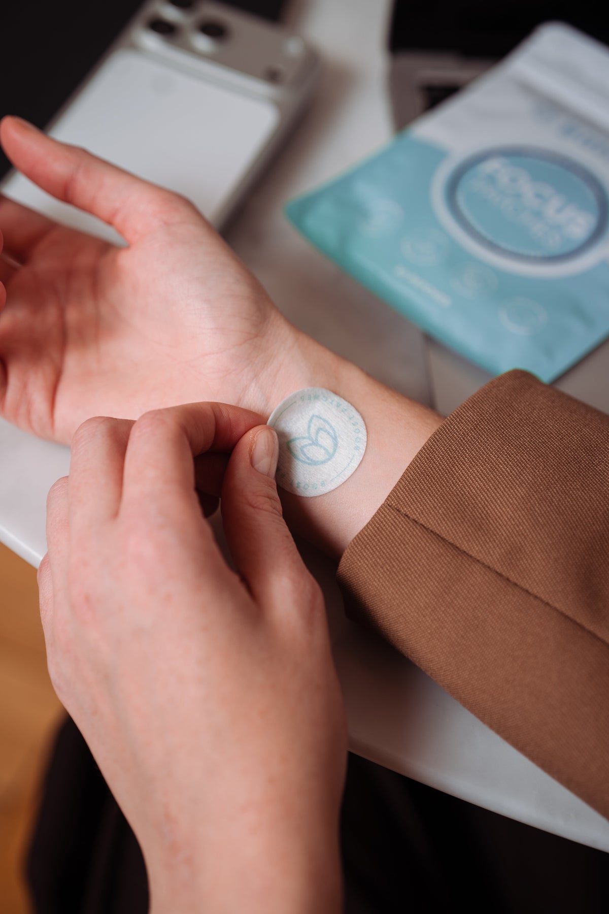 Person applying a wearable wellness patch during a modern daily routine